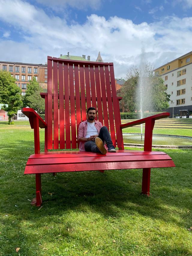 A man is sitting on a giant red chair